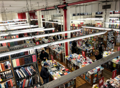 Aerial view of a busy bookstore with shelves filled with books and customers browsing the aisles.