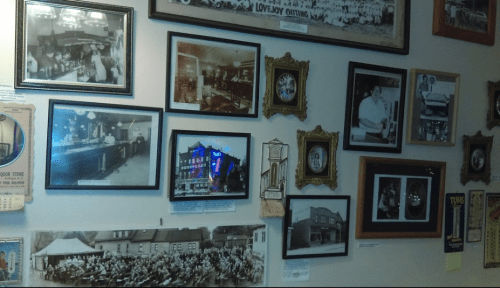 A collage of historical black-and-white photos and framed images displayed on a wall, showcasing various scenes and events.