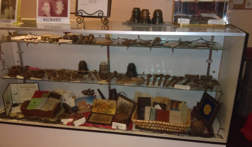 Display case filled with various historical artifacts, tools, and certificates, showcasing a collection of memorabilia.
