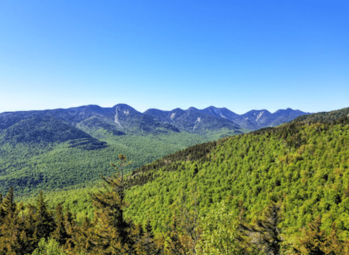 A panoramic view of lush green mountains under a clear blue sky.