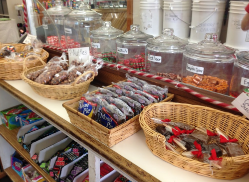 A display of various candies in glass jars and baskets, including chocolate treats and nostalgic sweets.