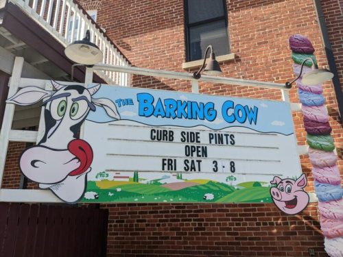 Sign for "The Barking Cow" featuring a cartoon cow and pig, advertising curbside pints and open hours on Fri and Sat.