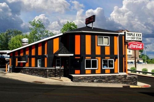 A colorful restaurant with orange and black stripes, featuring a sign for "Triple XXX" and a Coca-Cola advertisement.