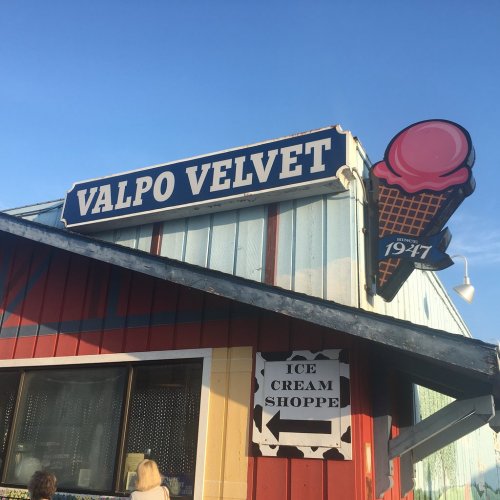 Sign for Valpo Velvet ice cream shop, featuring a large ice cream cone graphic and a bright blue sky.