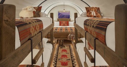 Cozy interior of a glamping tent with bunk beds, decorative blankets, and plush toys. Warm, inviting atmosphere.