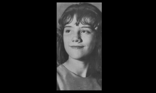 Black and white portrait of a young woman with wavy hair, smiling softly and looking to the side.