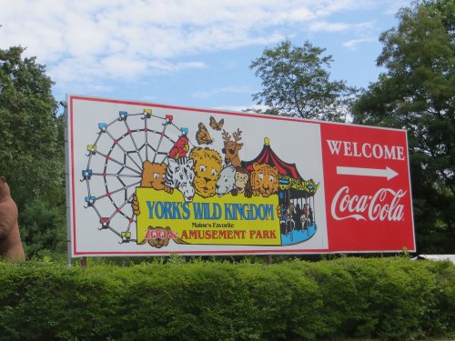 Sign for York's Wild Kingdom, featuring a zoo and amusement park, with a ferris wheel and colorful graphics.