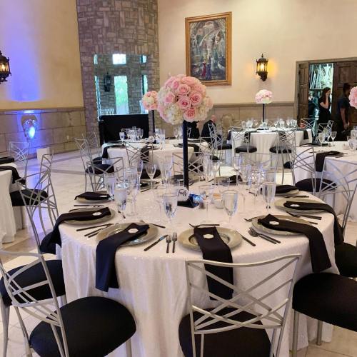 Elegant dining setup with round tables, black and white decor, floral centerpieces, and sparkling glassware.