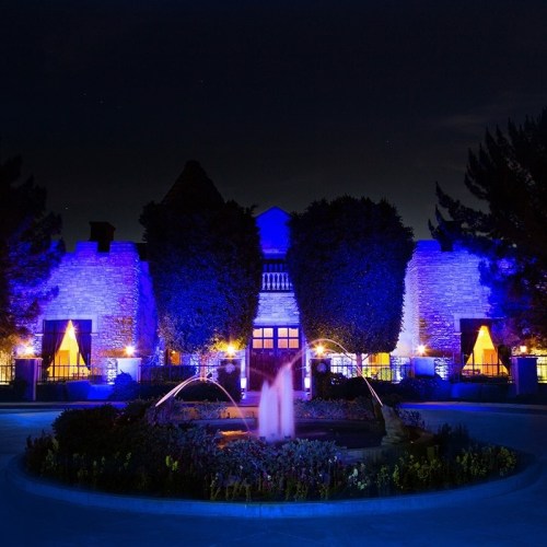 A beautifully lit building at night, surrounded by trees and a fountain, creating a serene atmosphere.