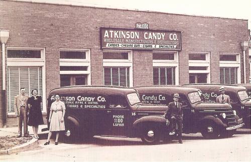 Historic photo of Atkinson Candy Co. with vintage delivery trucks and employees outside the building.