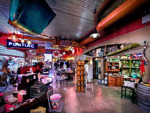 A vibrant antique shop filled with vintage signs, furniture, and collectibles in a spacious, well-lit interior.