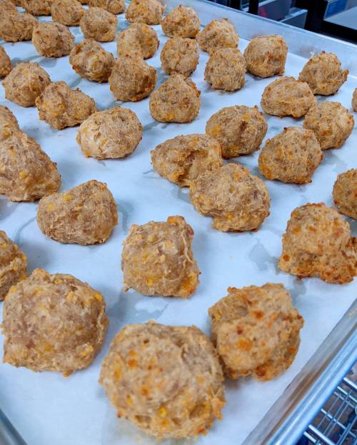 A tray of golden-brown, round dough balls on parchment paper, freshly baked and ready to be served.