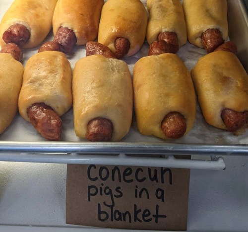 A tray of "Conecun pigs in a blanket," featuring sausages wrapped in golden-brown dough.
