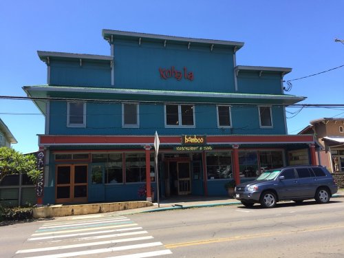 Colorful building with "Kohala" sign, featuring a restaurant named "Bamboo" on the ground floor, parked car in front.