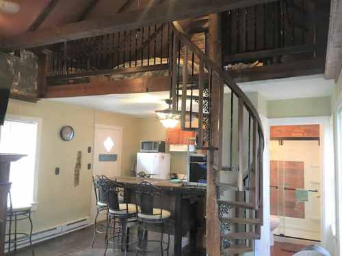 Cozy interior of a home featuring a spiral staircase, kitchen area, and a lofted sleeping space above.