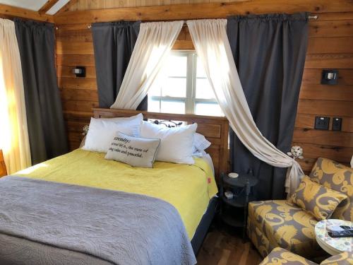 Cozy bedroom with a yellow and gray color scheme, featuring a wooden bed, curtains, and a patterned chair.