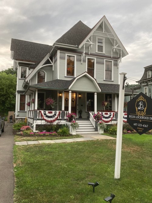 Victorian-style house with decorative trim, flower beds, and a sign for Belva Lockwood Inn.