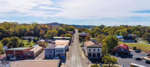 Aerial view of a small town with colorful trees, shops, and a clear blue sky in the background.