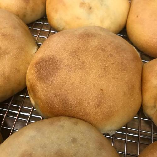Freshly baked golden-brown bread rolls cooling on a wire rack.