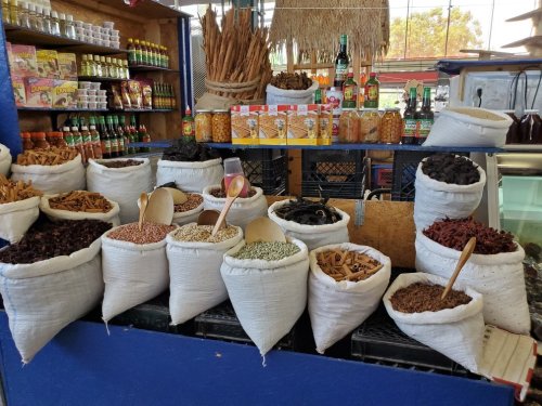 A colorful display of various spices and herbs in burlap sacks at a market stall.