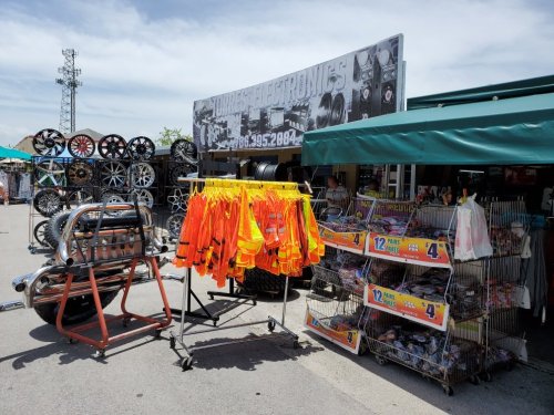 A market stall displaying safety vests, wheels, and various items for sale under a clear blue sky.