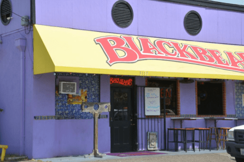Exterior of a purple building with a yellow awning, featuring the sign "BLACKBEARD" and a decorative entrance.