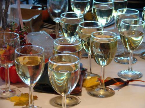 A table set with numerous glasses of white wine, surrounded by autumn leaves and festive decorations.