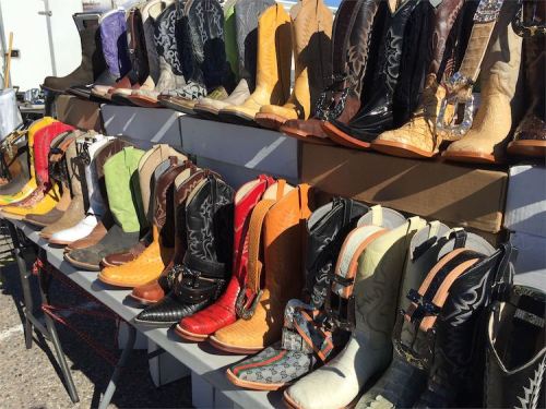 A display of various styles and colors of cowboy boots arranged on tables.