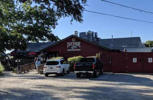 Exterior of Dockside Restaurant with cars parked outside and people entering on a sunny day.