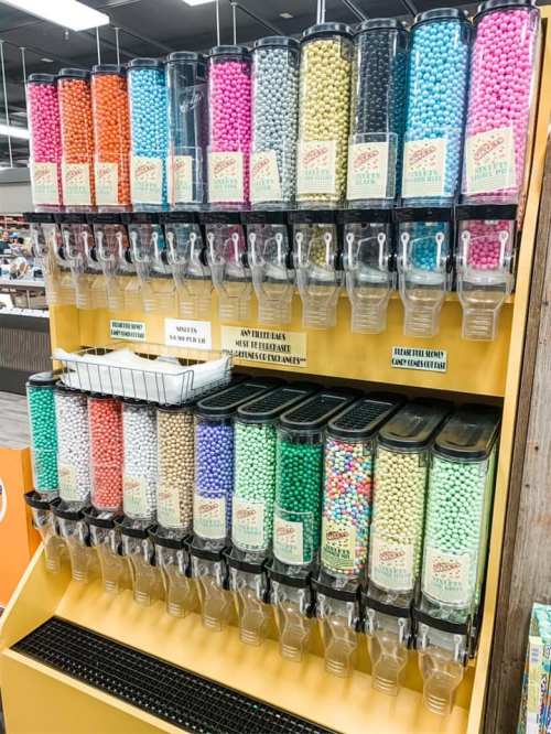 A colorful display of candy dispensers filled with various types of candy in clear containers.