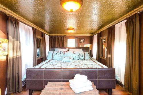 Cozy bedroom with a large bed, decorative pillows, and elegant curtains, featuring a vintage ceiling and warm lighting.
