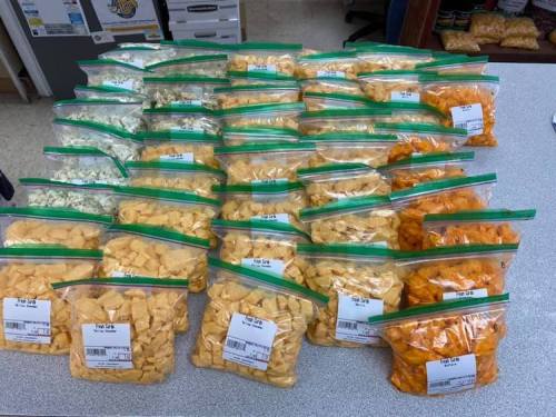 A table covered with multiple bags of colorful snacks, including orange, yellow, and white varieties, neatly arranged.