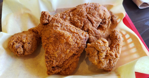 A basket of crispy fried chicken pieces on parchment paper.
