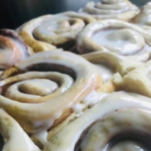 Close-up of freshly baked cinnamon rolls drizzled with creamy icing.