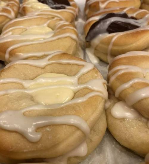 Close-up of soft, glazed pastries with creamy filling and drizzled icing on top.