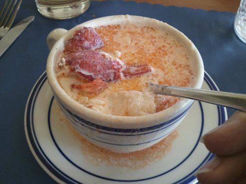 A cup filled with creamy dessert, topped with strawberry pieces and a spoon resting on the side.