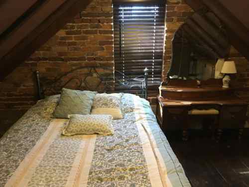 Cozy attic bedroom with a brick wall, a bed with patterned bedding, and a wooden dresser with a mirror.