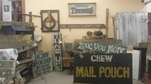 A collection of vintage wooden signs displayed in a rustic shop, featuring various playful phrases and designs.