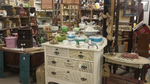 A vintage shop filled with various antiques, including furniture, dishes, and decorative items on display.