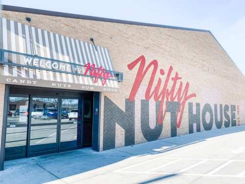 Exterior of a building with a large mural reading "Nifty Nut House" and a sign welcoming visitors.