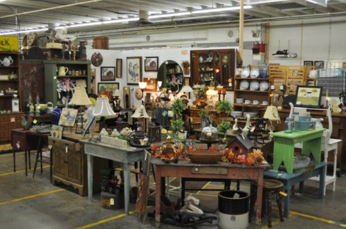 A cozy antique shop filled with various vintage furniture, decor items, and lamps arranged on tables and shelves.