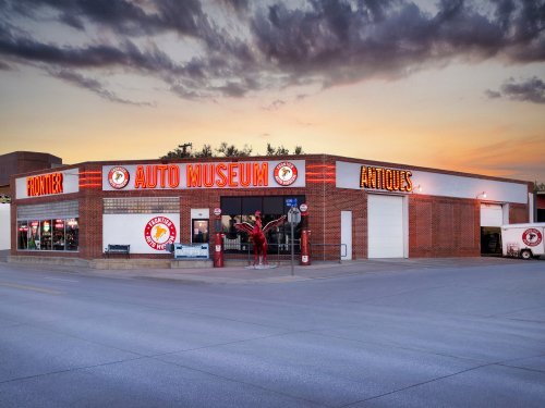 Front view of the Frontier Auto Museum at sunset, featuring vintage cars and antique displays.