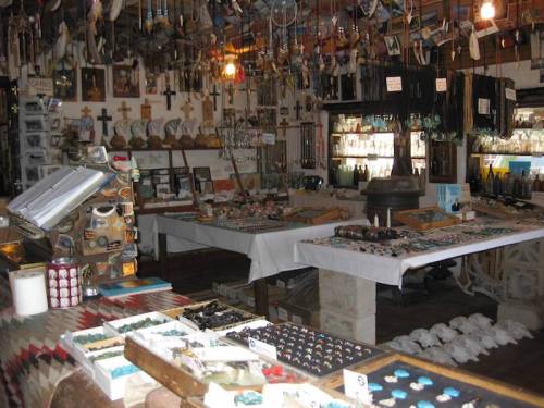 A cozy shop filled with various crafts, jewelry, and decorations, including crosses and colorful stones on display.
