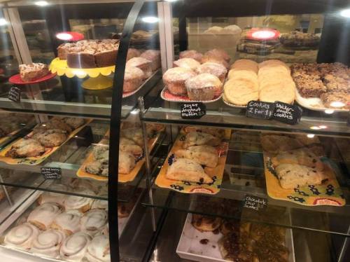 A display case filled with various baked goods, including muffins, cookies, and pastries.