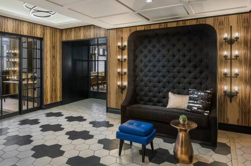 A stylish lobby with a tufted black seating area, hexagonal tile floor, and modern lighting fixtures.