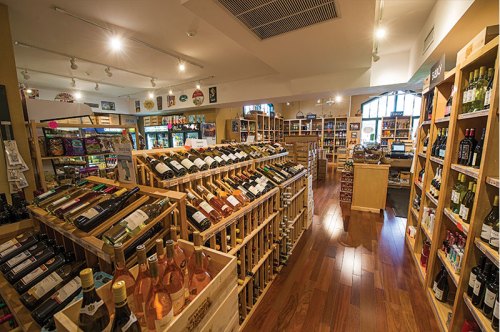 A well-organized wine shop with wooden shelves displaying various bottles and a warm, inviting atmosphere.