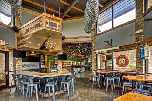 Modern bar interior with a circular counter, colorful lighting, and a mix of high-top and regular seating.
