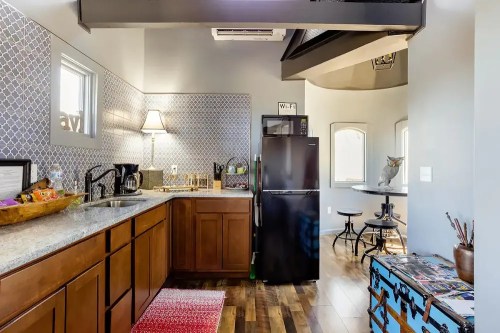 Modern kitchen with wooden cabinets, a black fridge, and a cozy dining area featuring a round table and decorative accents.