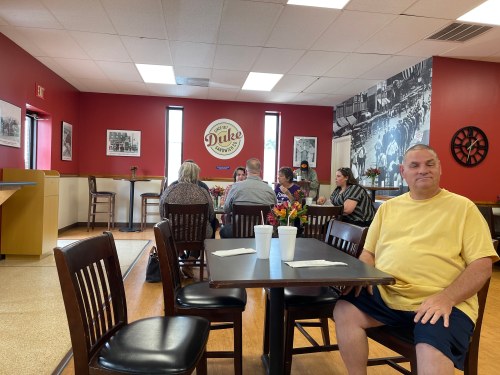 A casual dining area with tables, patrons enjoying their meals, and a wall featuring black-and-white photos.