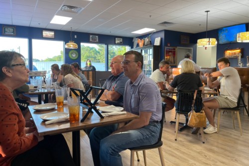 A busy restaurant scene with diners at tables, chatting and enjoying their meals in a casual atmosphere.